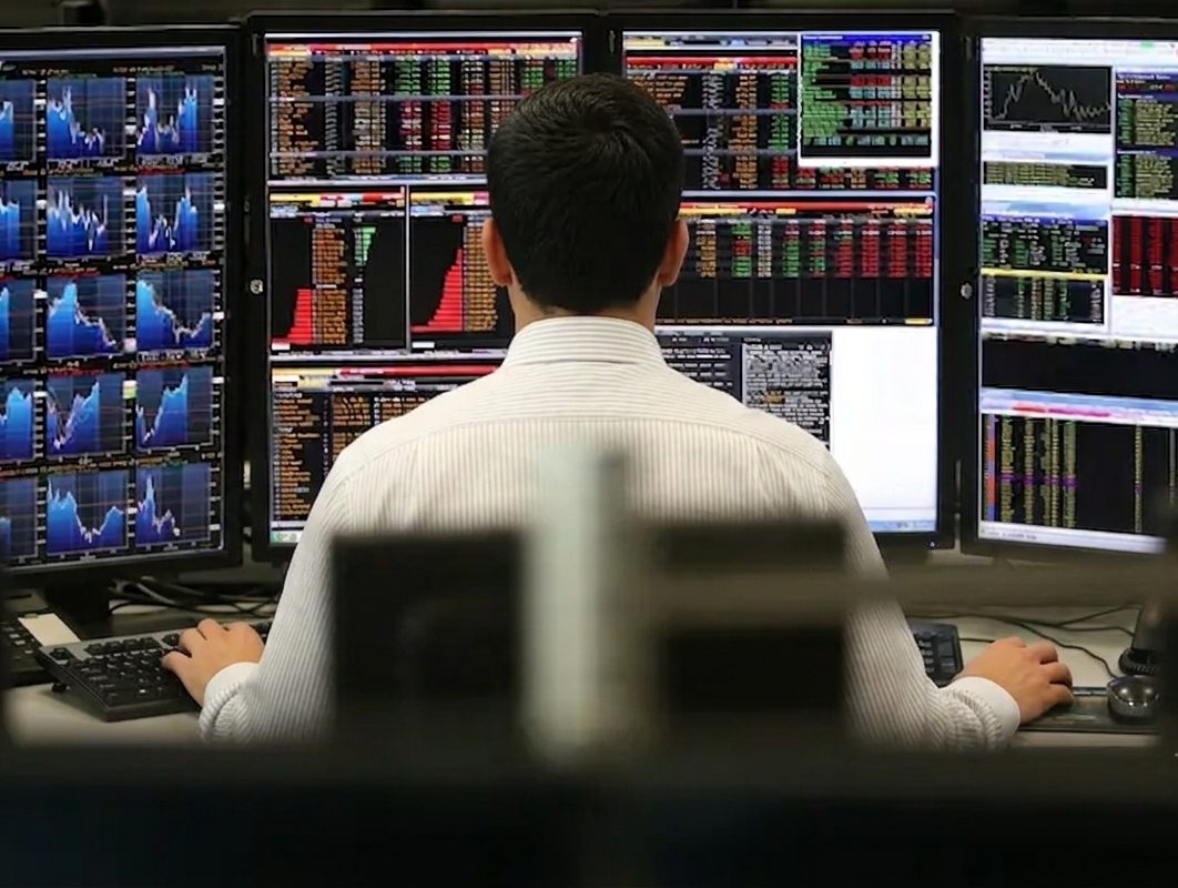 Trader analyzing markets across a multi-monitor desk at a New York City quant trading firm